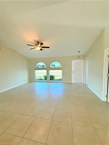 Spare room with ceiling fan, vaulted ceiling, and light tile patterned flooring