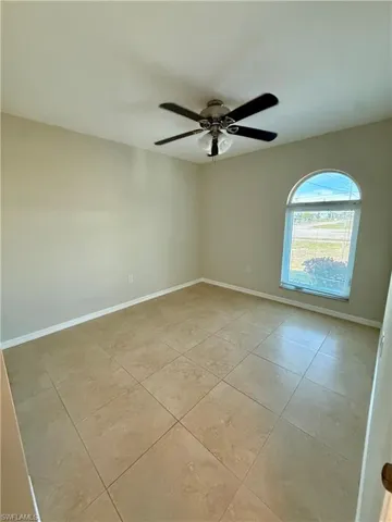 Empty room featuring light tile patterned flooring and a ceiling fan