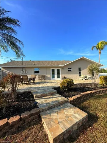 Back of house featuring a patio area, stucco siding, and a shingled roof