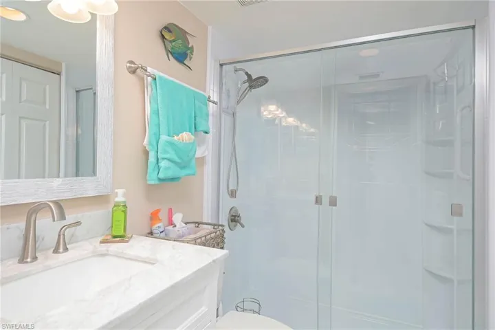 Bathroom featuring vanity, toilet, and an enclosed shower