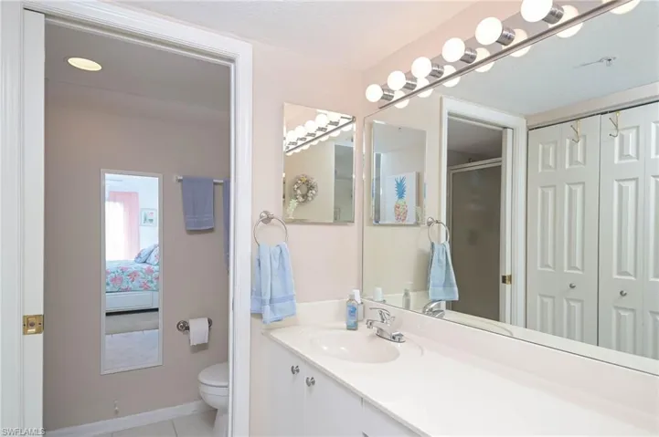 Bathroom featuring tile patterned flooring, a shower with door, vanity, and toilet