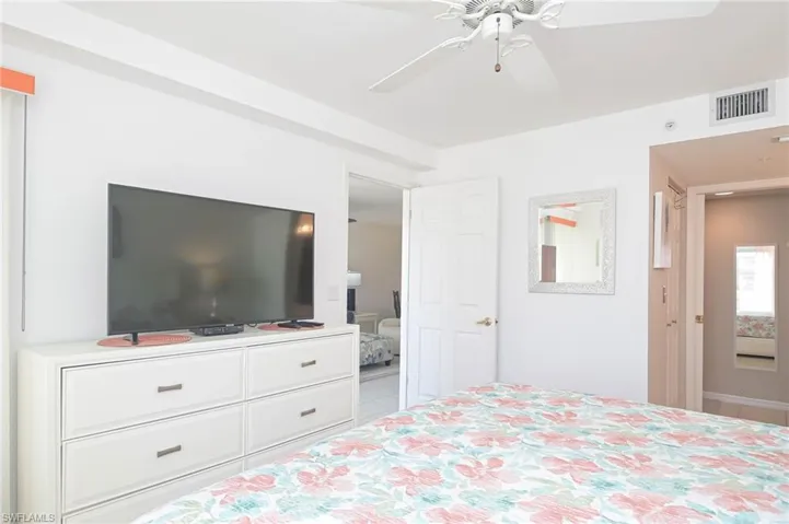 Tiled bedroom featuring ensuite bath and ceiling fan