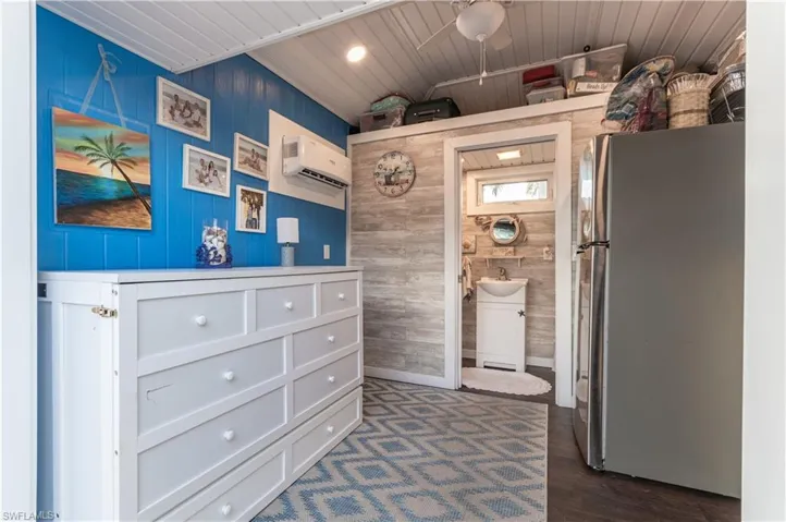 Bathroom featuring wood walls, vanity, dark wood-style flooring, ceiling fan, and a wall mounted AC