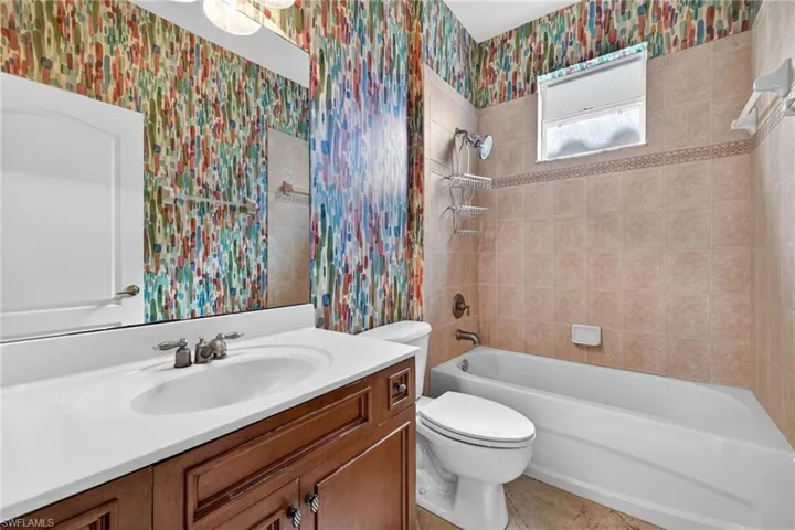 Full bathroom featuring vanity, wallpapered walls, and shower / tub combination