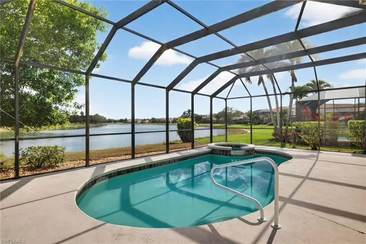 Combined pool / hot tub featuring glass enclosure, a sunroom, and a water view