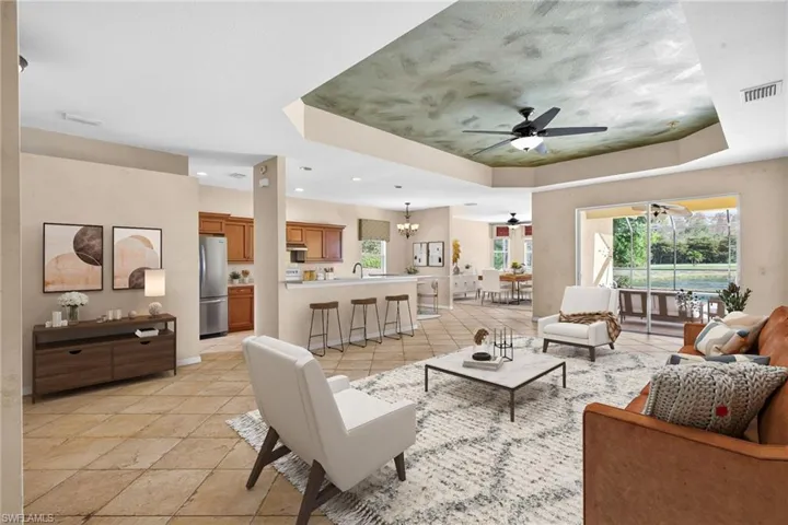 Living room with suspended lighting, healthy amount of natural light, a tray ceiling, ceiling fan, and light tile patterned flooring