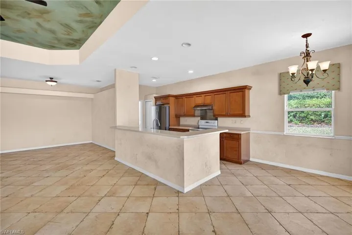 Kitchen with wood finish cabinetry, hanging lights, light countertops, and freestanding refrigerator