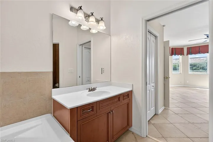 Full bath with vanity, a bath, a closet, a textured wall, and light tile patterned floors