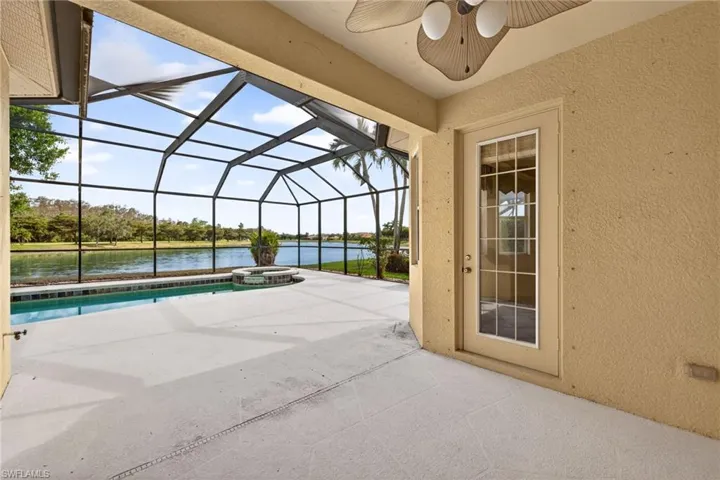 View of patio with a sunroom, glass enclosure, a pool with connected hot tub, a water view, and a ceiling fan