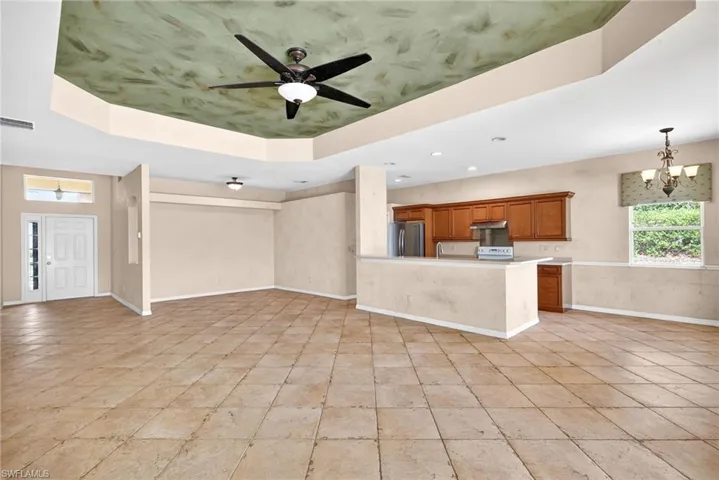 Unfurnished living room with a tray ceiling, ceiling fan, and suspended lighting
