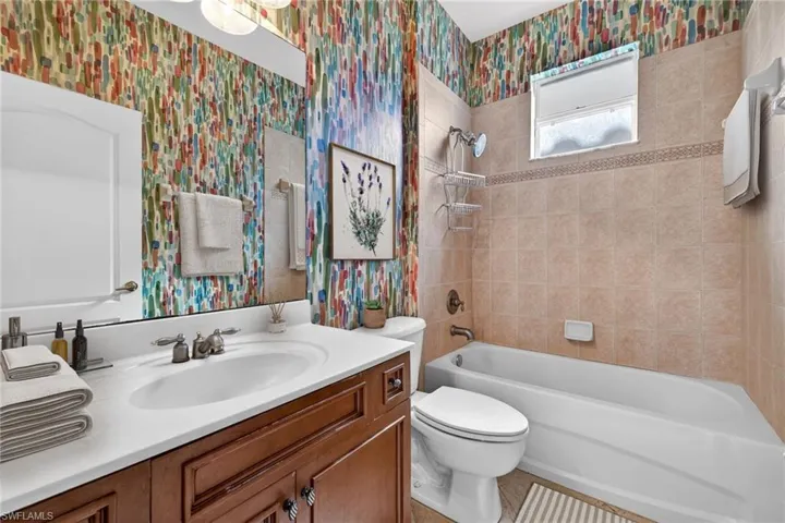Full bath with wallpapered walls, vanity, and tub / shower combination