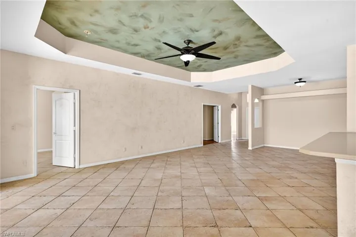Spare room with a tray ceiling, a ceiling fan, and arched walkways