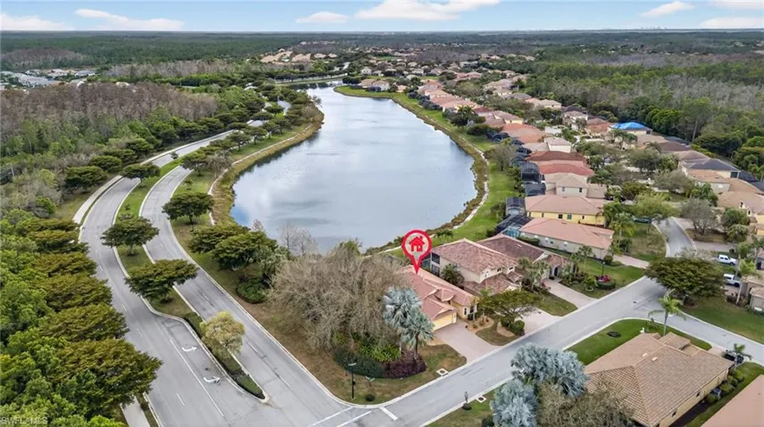 Aerial perspective of suburban area featuring a heavily wooded area and a nearby body of water