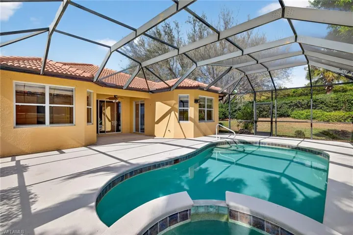 Combined pool / hot tub with a sunroom, glass enclosure, and a patio area