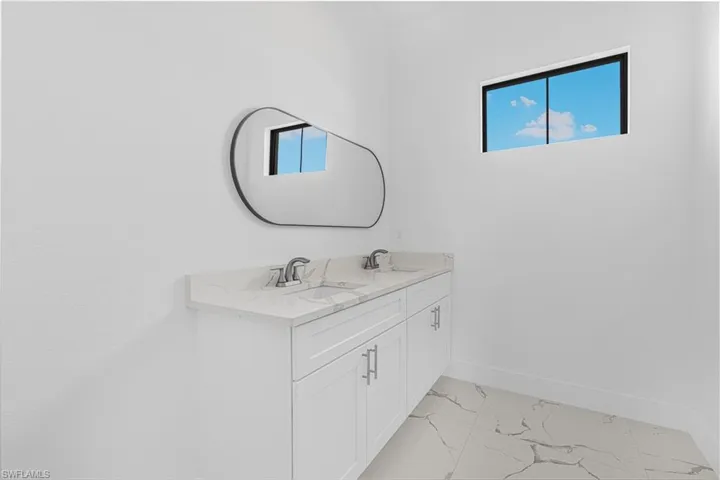 Bathroom featuring baseboards, marble finish floor, a wealth of natural light, and a sink