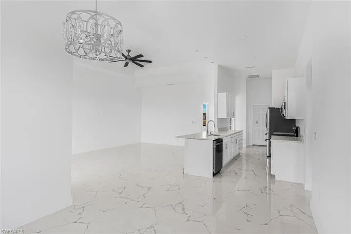 Kitchen with a sink, dishwashing machine, marble finish floor, and white cabinetry