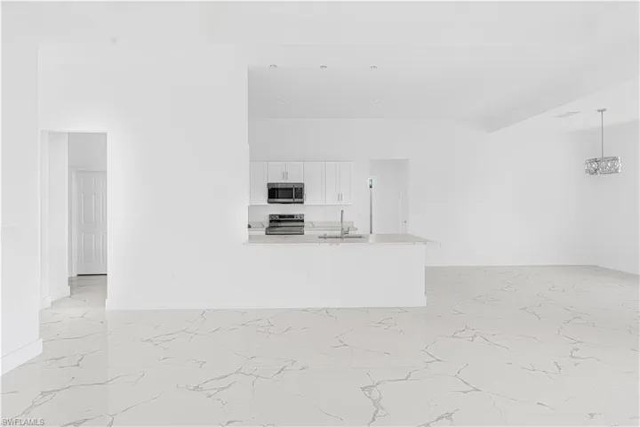 Kitchen featuring light countertops, white cabinets, marble finish floor, and stainless steel appliances