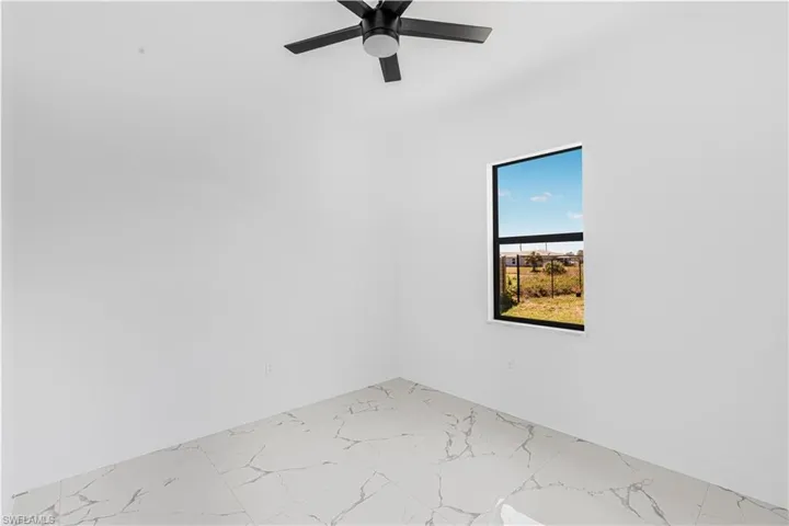 Unfurnished room featuring marble finish floor and ceiling fan