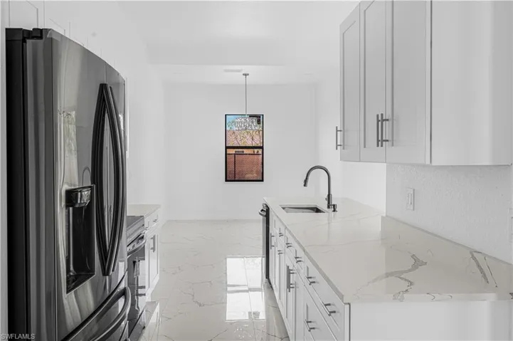 Kitchen with a sink, marble finish floor, white cabinets, and stainless steel fridge with ice dispenser
