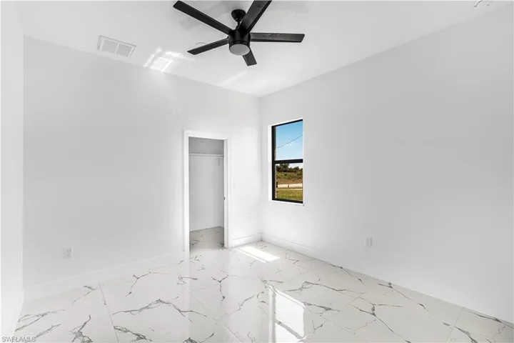 Unfurnished bedroom featuring visible vents, marble finish floor, a closet, baseboards, and ceiling fan