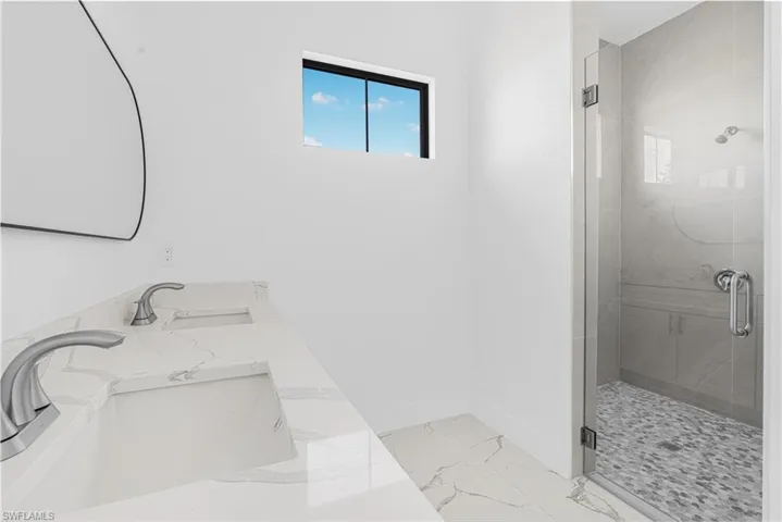Full bath featuring a stall shower, baseboards, marble finish floor, and a sink