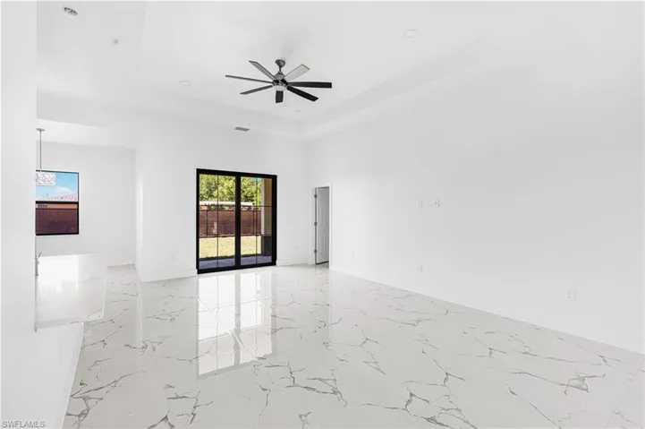Empty room with visible vents, baseboards, ceiling fan, a tray ceiling, and marble finish floor