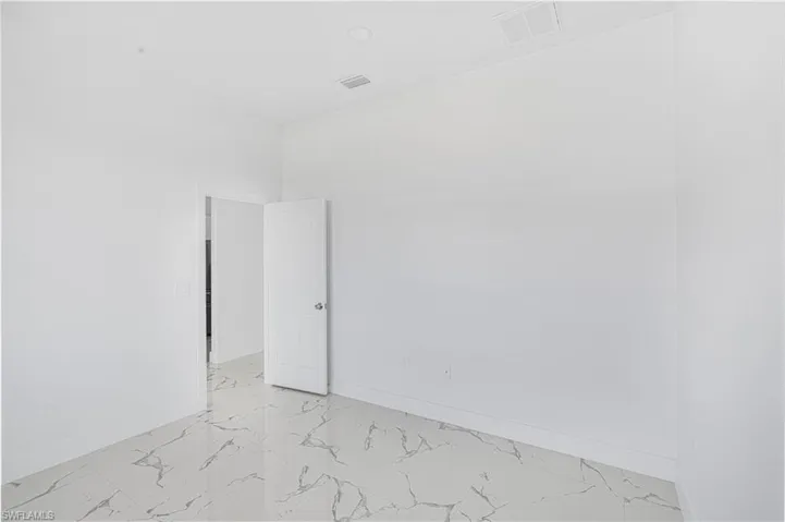 Empty room featuring visible vents, marble finish floor, and baseboards