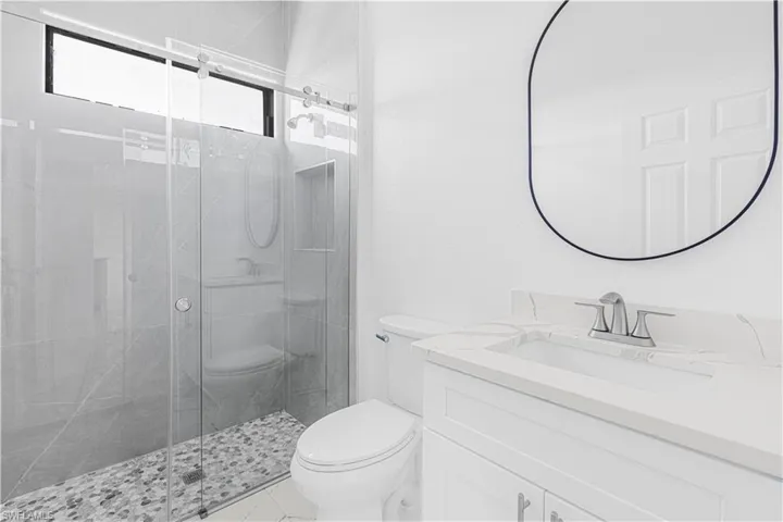 Bathroom with vanity, toilet, a stall shower, and marble finish floor