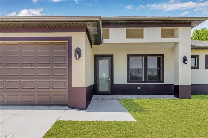 View of front of property featuring stucco siding, an attached garage, and a front lawn
