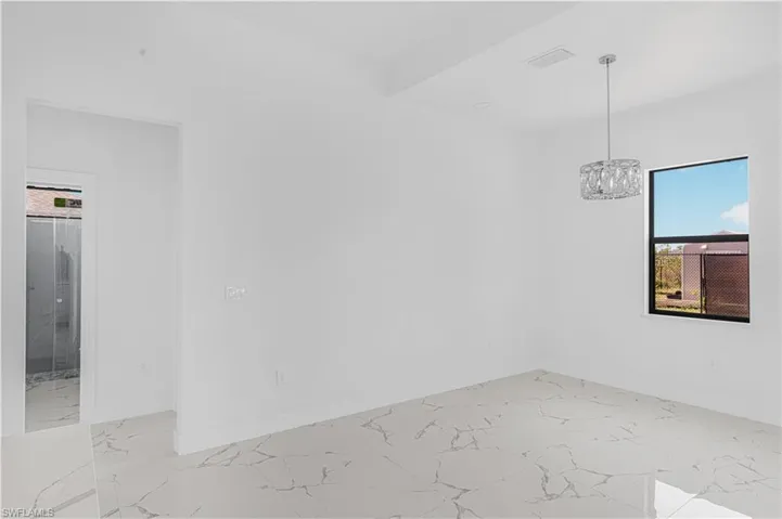 Unfurnished room featuring a chandelier, visible vents, marble finish floor, and baseboards
