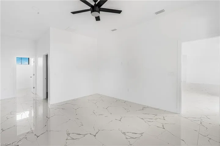 Empty room with visible vents, baseboards, marble finish floor, and ceiling fan
