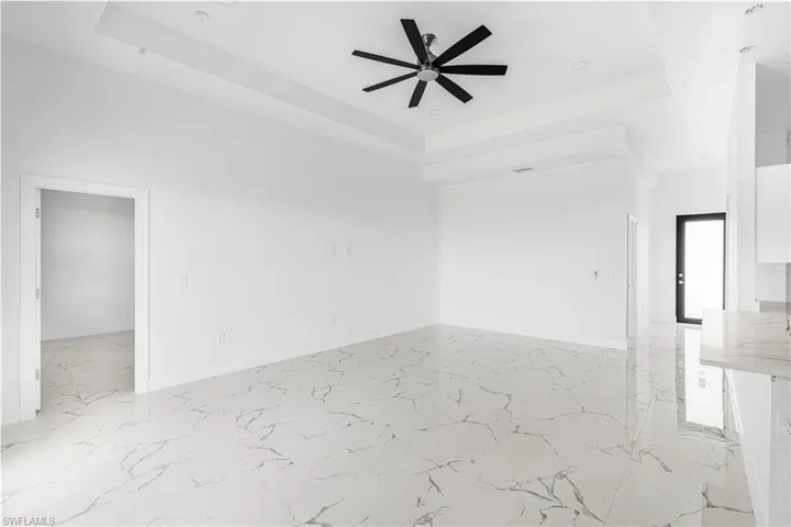 Unfurnished room with marble finish floor, baseboards, a raised ceiling, and a ceiling fan