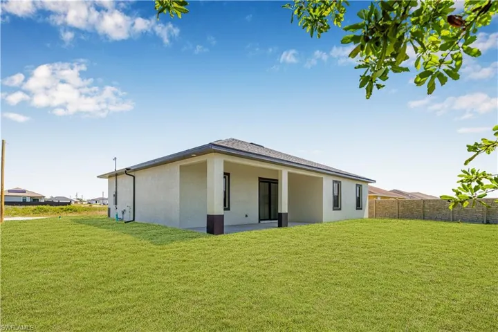 Back of house with fence, a lawn, and stucco siding