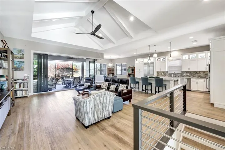 Living room featuring ceiling fan, light LVT floors, vaulted ceiling with beams
