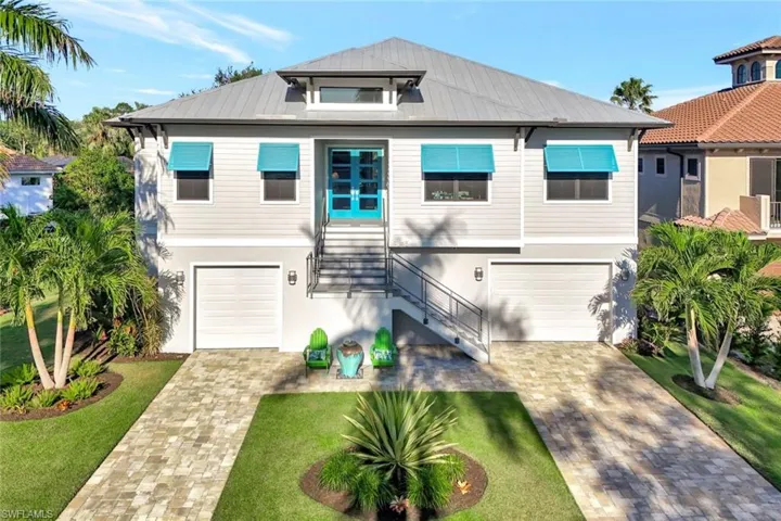 View of front of property featuring a fountain and brick paver driveway