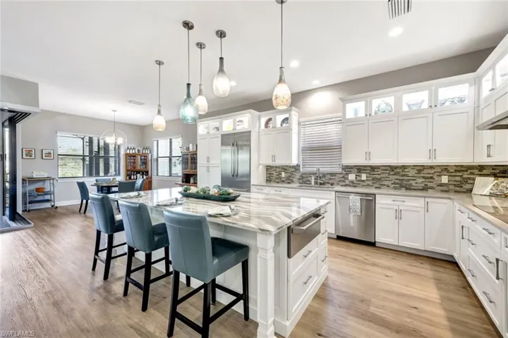 Kitchen with decorative light fixtures, white cabinetry, stainless steel appliances, and a kitchen island