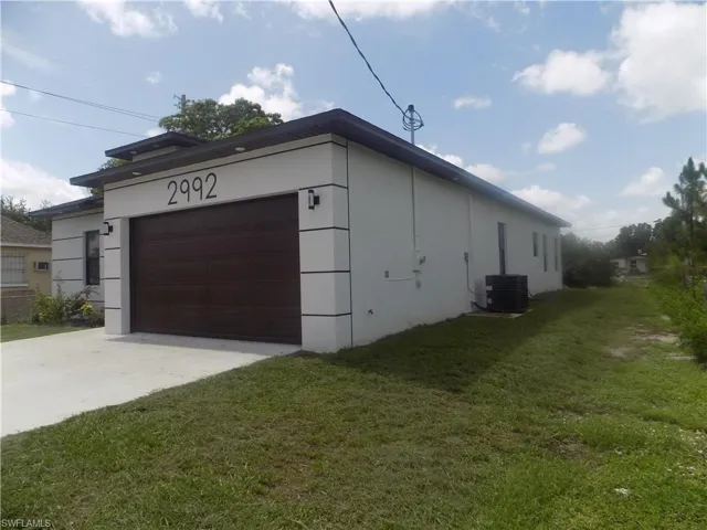 View of home's exterior featuring driveway, a lawn, stucco siding, and an attached garage