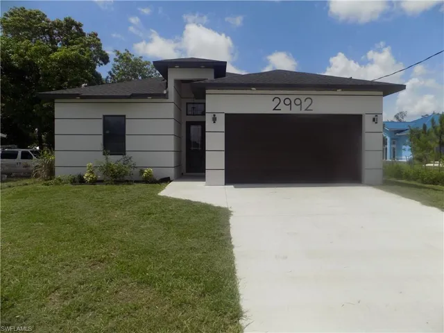 View of front of property featuring driveway, a garage, a front yard, and roof with shingles