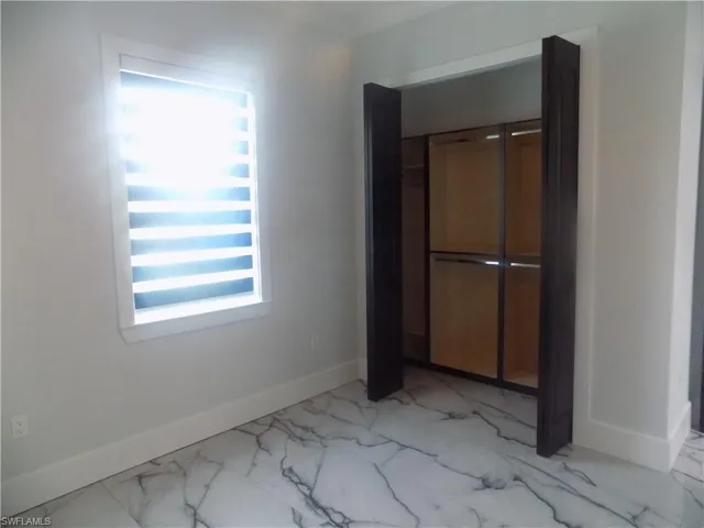 Unfurnished bedroom featuring light marble finish floors and a closet