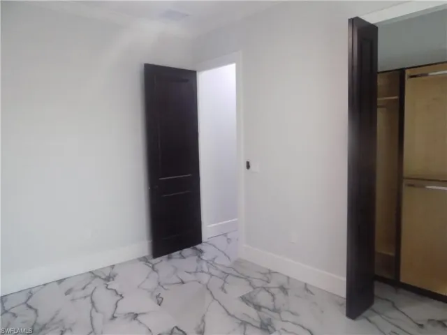 Unfurnished bedroom featuring light marble finish floors and crown molding