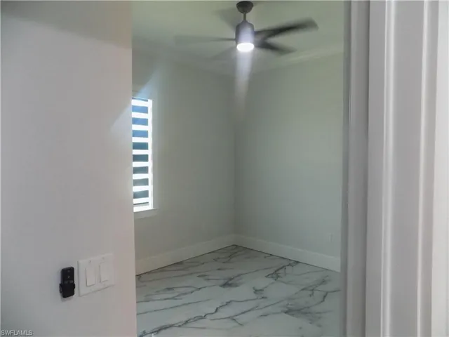 Spare room with crown molding, ceiling fan, and marble look tiles