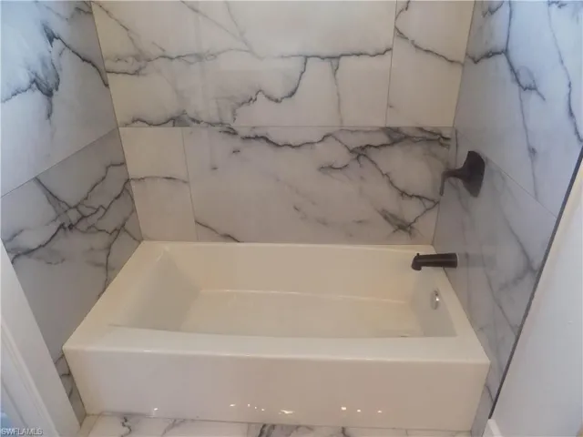 Bathroom featuring marble finish flooring and a bathtub