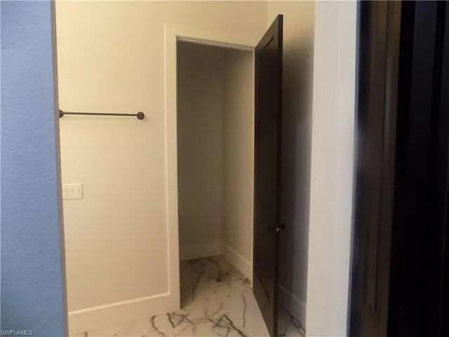 Bathroom with marble look tile flooring and baseboards