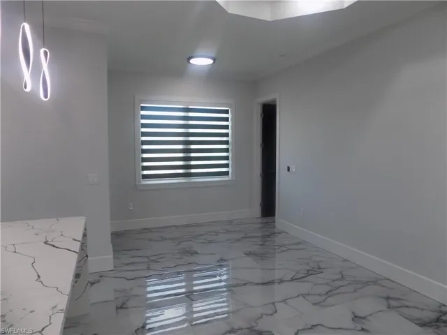 Empty room featuring marble look tile flooring and crown molding