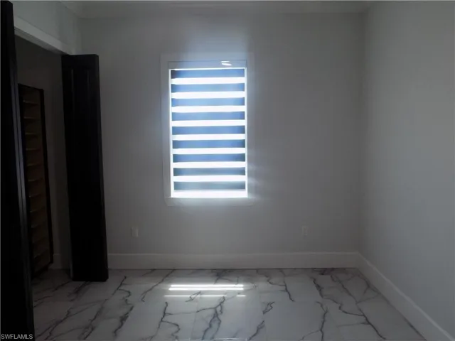 Unfurnished room featuring baseboards and marble look tiles
