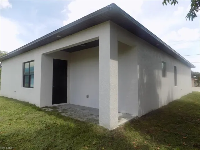 View of side of home with stucco siding and a lawn