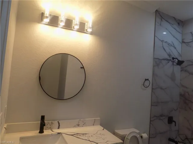 Full bath with vanity and a marble finish shower