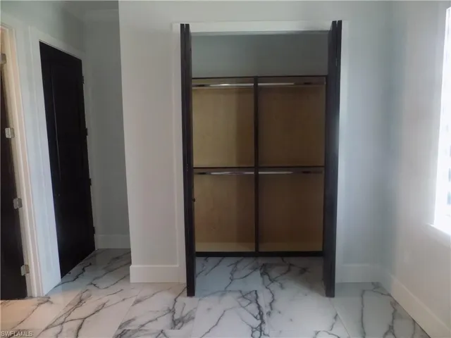 Unfurnished bedroom with marble look tiles and a closet