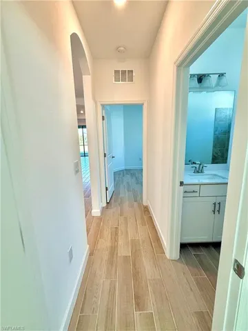 Corridor with wood finish floors and arched walkways