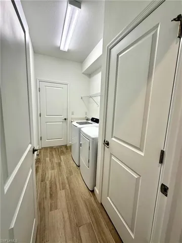 Washroom featuring light wood-style floors, independent washer and dryer, and a textured ceiling